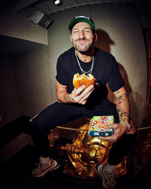 Rumble Boxing co-founder Noah Neiman eating the Knockout Burger with his beloved sandwich box in his other hand. (Delicious photo by Mark Grgurich for Rumble)