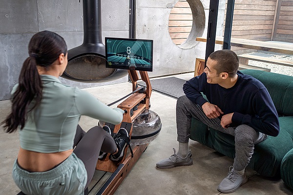 Woman on Ergatta Rower as man watches