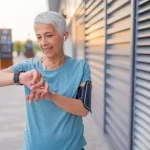 Smiling older woman looking at her fitness wearable