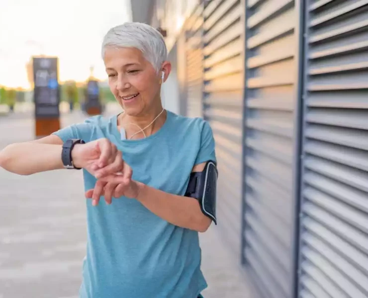 Smiling older woman looking at her fitness wearable
