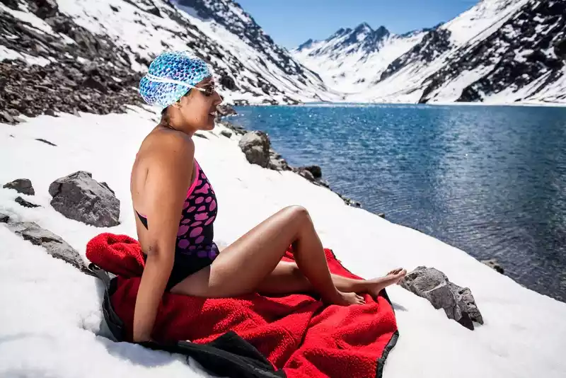Bárbara Hernández sitting in swimsuit on icy land adjoining Antarctic Ocean