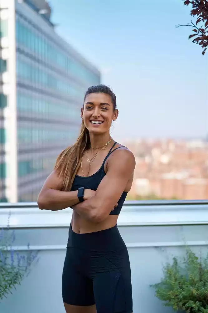 Meghan Hayden smiling with hands folded and showing biceps