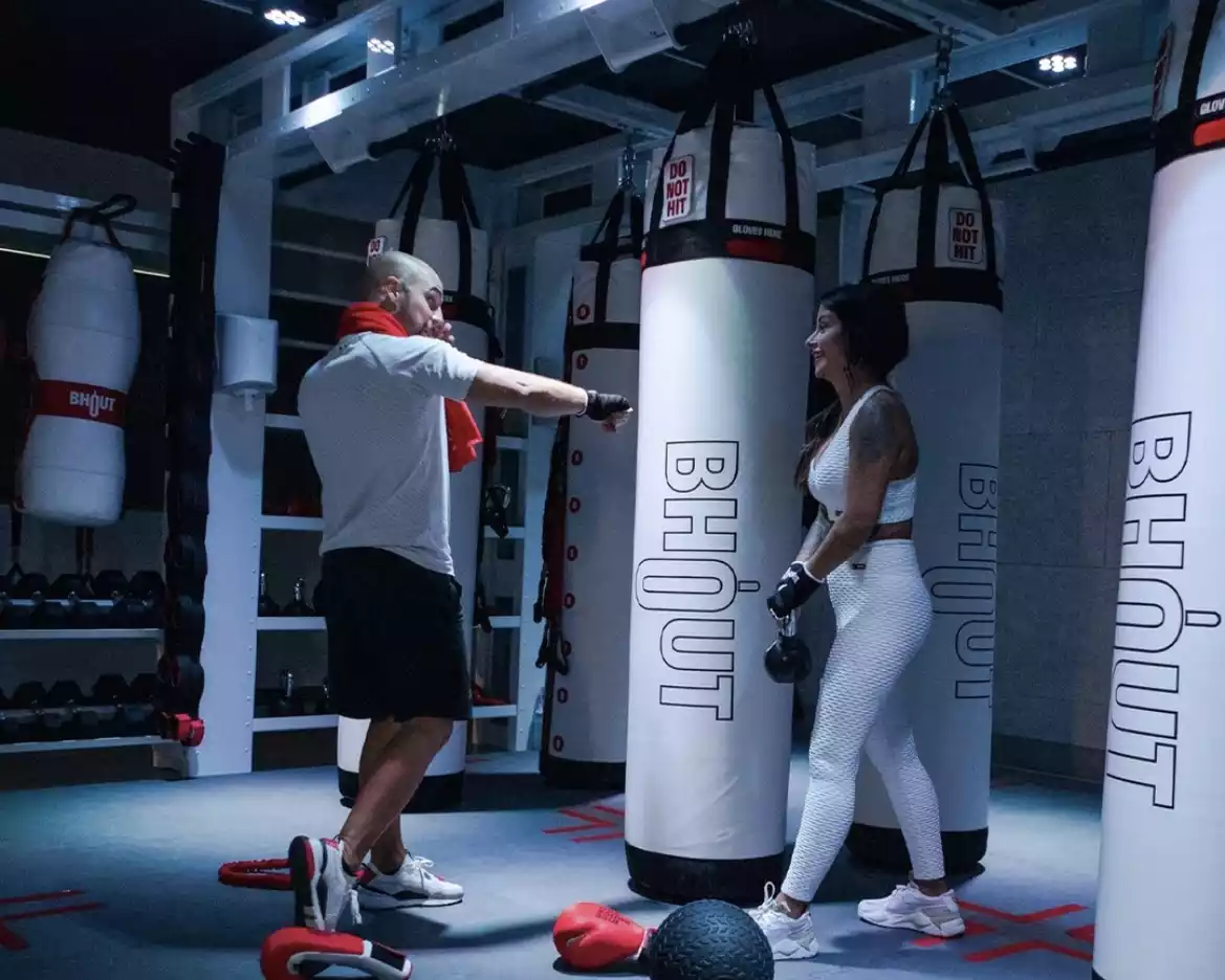 Man punching Bhout, the boxing bag with a brain, while a woman watches.