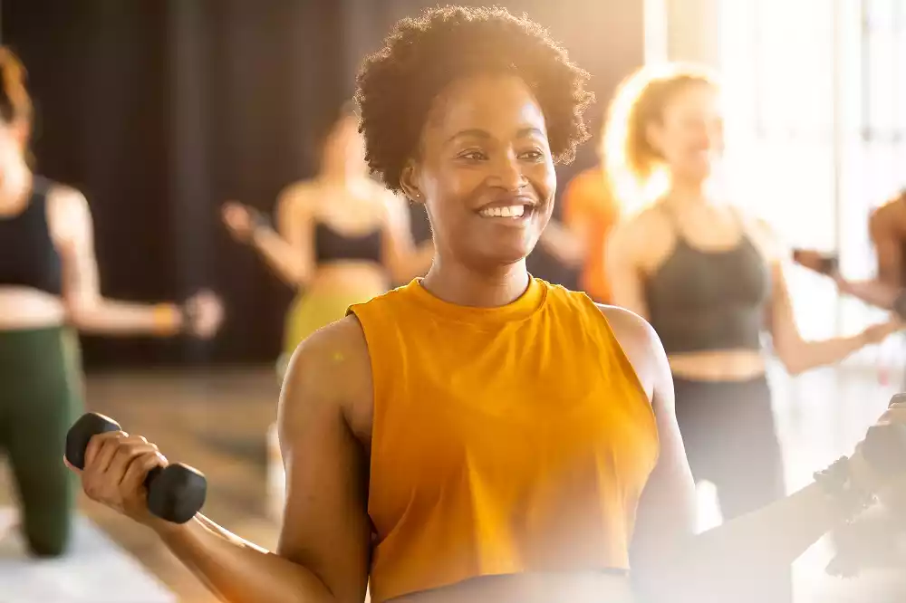 A young black woman doing yoga with dumbbells at a CorePower Yoga session