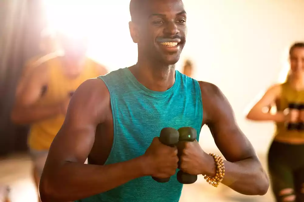 A black man doing yoga with dumbbells at a CorePower Yoga session