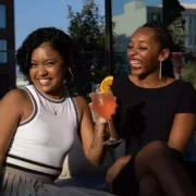 Two black women laughing and having drinks