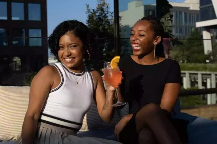 Two black women laughing and having drinks