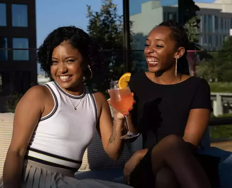 Two black women laughing and having drinks