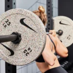 woman works out with Nike barbell and bumper plates
