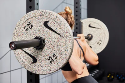 woman works out with Nike barbell and bumper plates