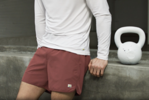 man poses next to a kettlebell in Vuori shorts