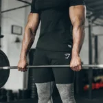 man lifts a barbell wearing Gymshark shorts