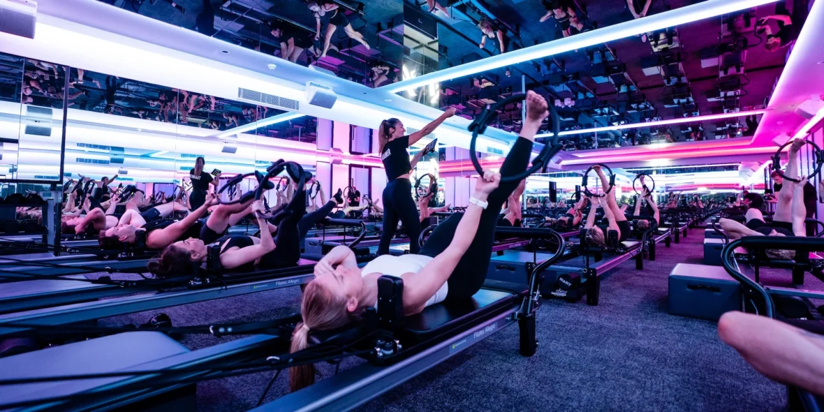 woman works out on a Reformer inside a Vaura Pilates studio, owned by F45