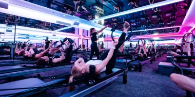 woman works out on a Reformer inside a Vaura Pilates studio, owned by F45