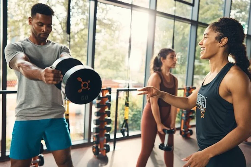 man lifts a dumbbell at an Orangetheory studio