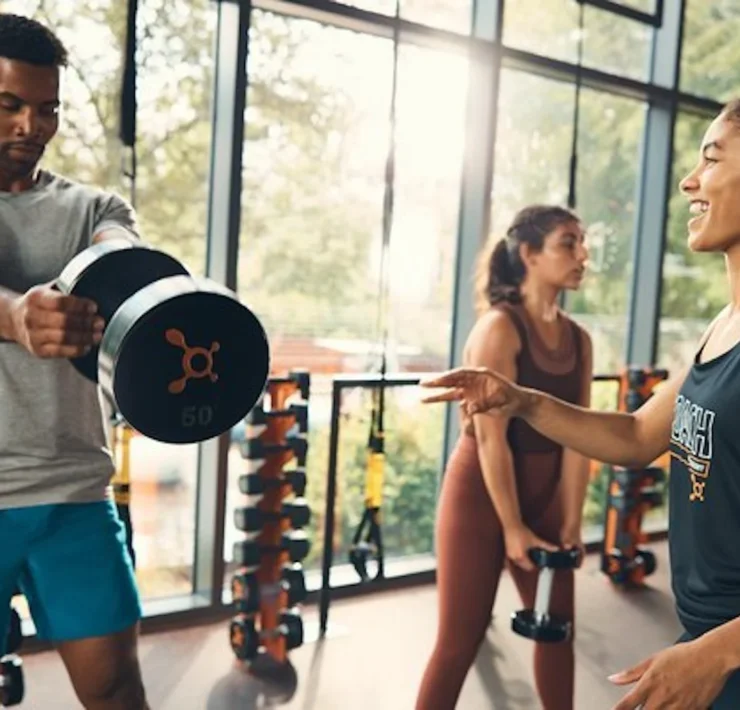 man lifts a dumbbell at an Orangetheory studio