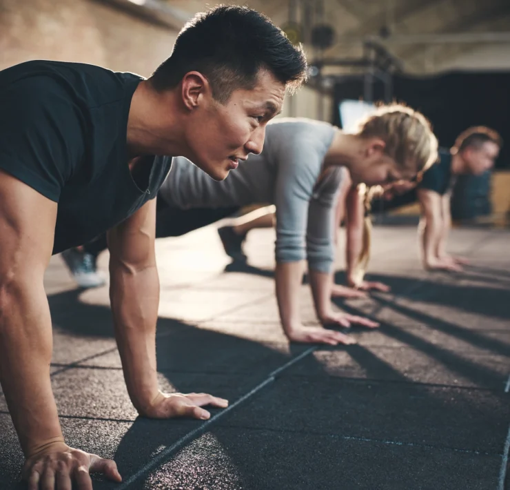 men and women perform planks inside a gym