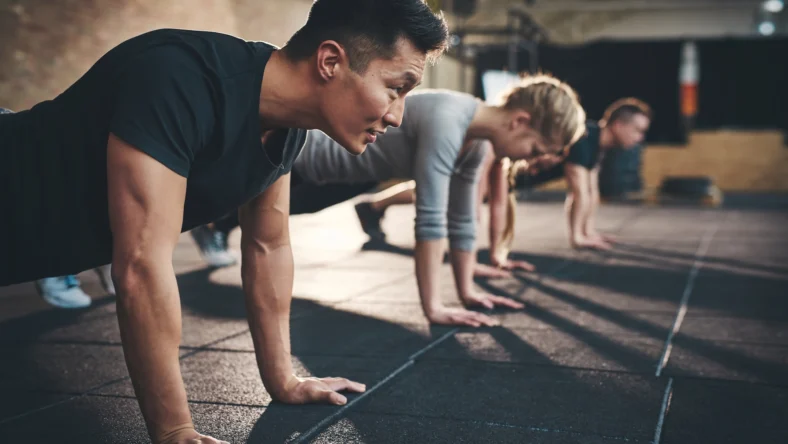 men and women perform planks inside a gym