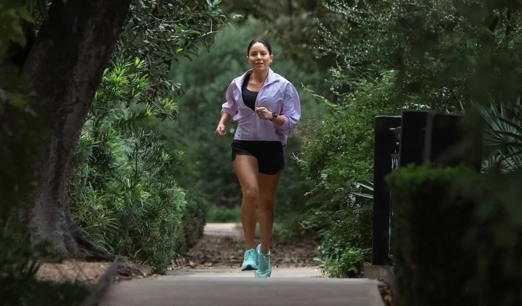 woman runs on a tree-lined path