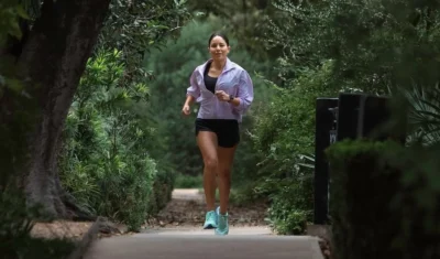 woman runs on a tree-lined path