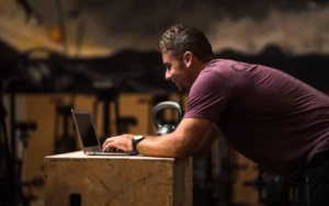man types on his laptop on a wooden desk