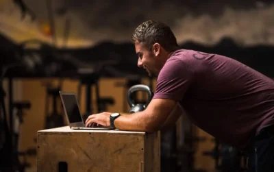 man types on his laptop on a wooden desk
