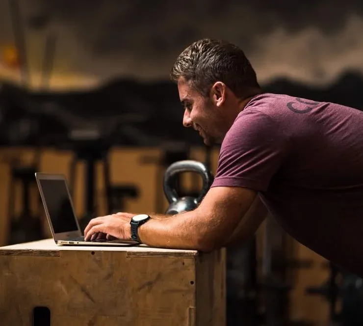 man types on his laptop on a wooden desk