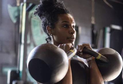 Young Black woman doing a double kettlebell hold