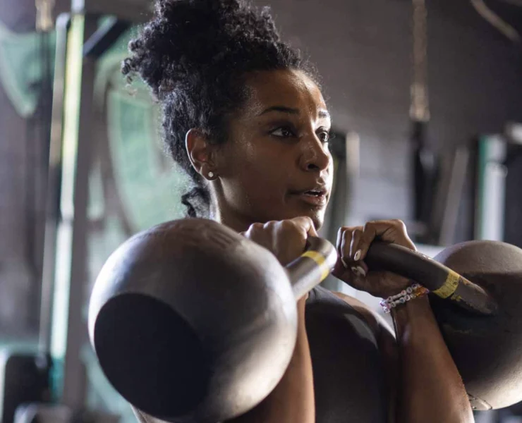 Young Black woman doing a double kettlebell hold