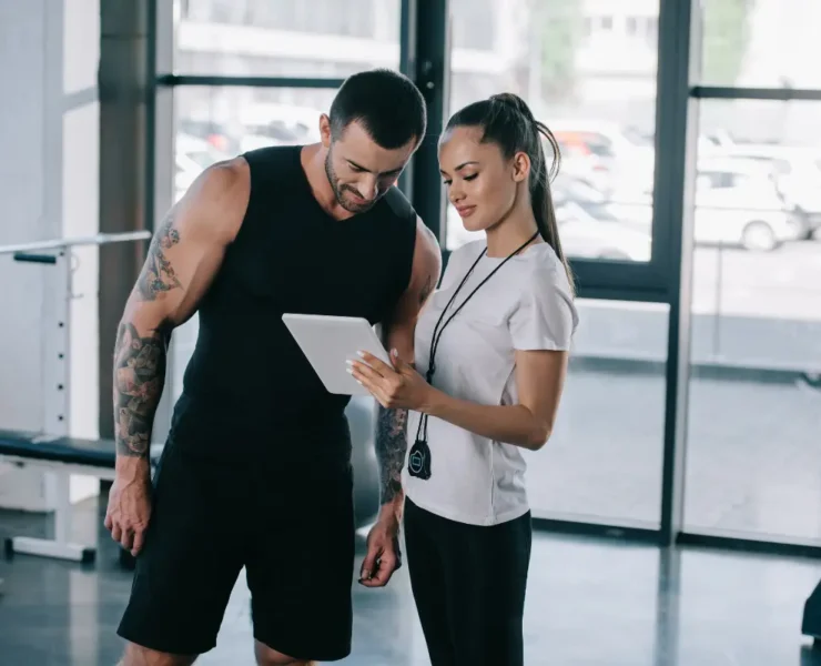 Man and woman at gym looking at smart tablet