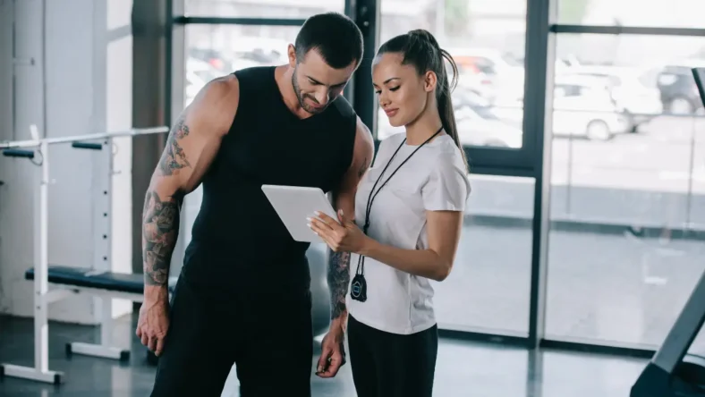 Man and woman at gym looking at smart tablet