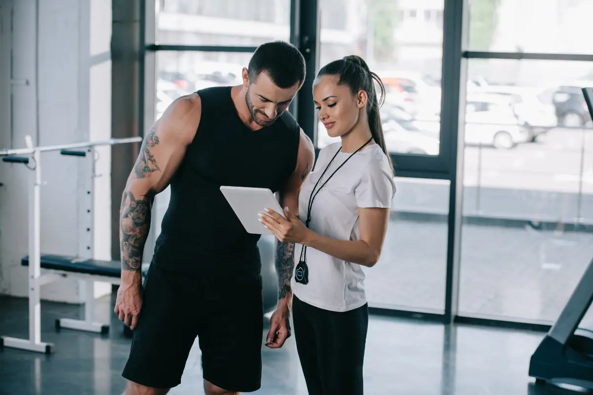 Man and woman at gym looking at smart tablet