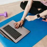 Woman on a yoga mat looking at laptop