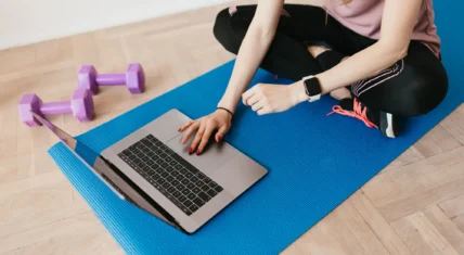 Woman on a yoga mat looking at laptop