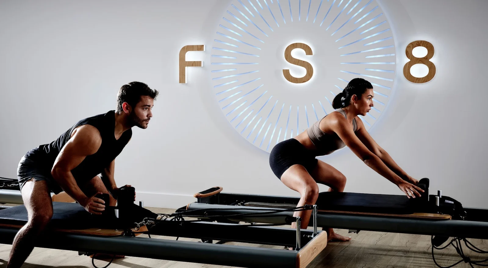 Man and woman on Pilates reformers