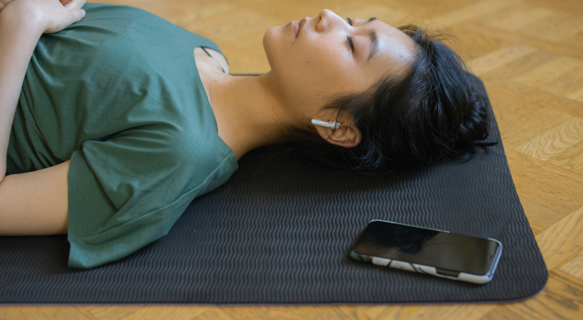 Woman lying on yoga mat eyes closed
