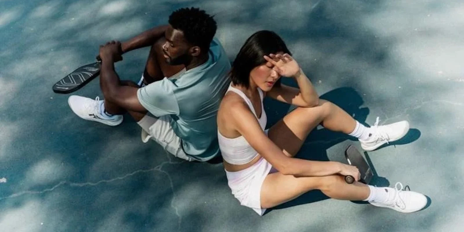 man and woman sitting down on tennis court