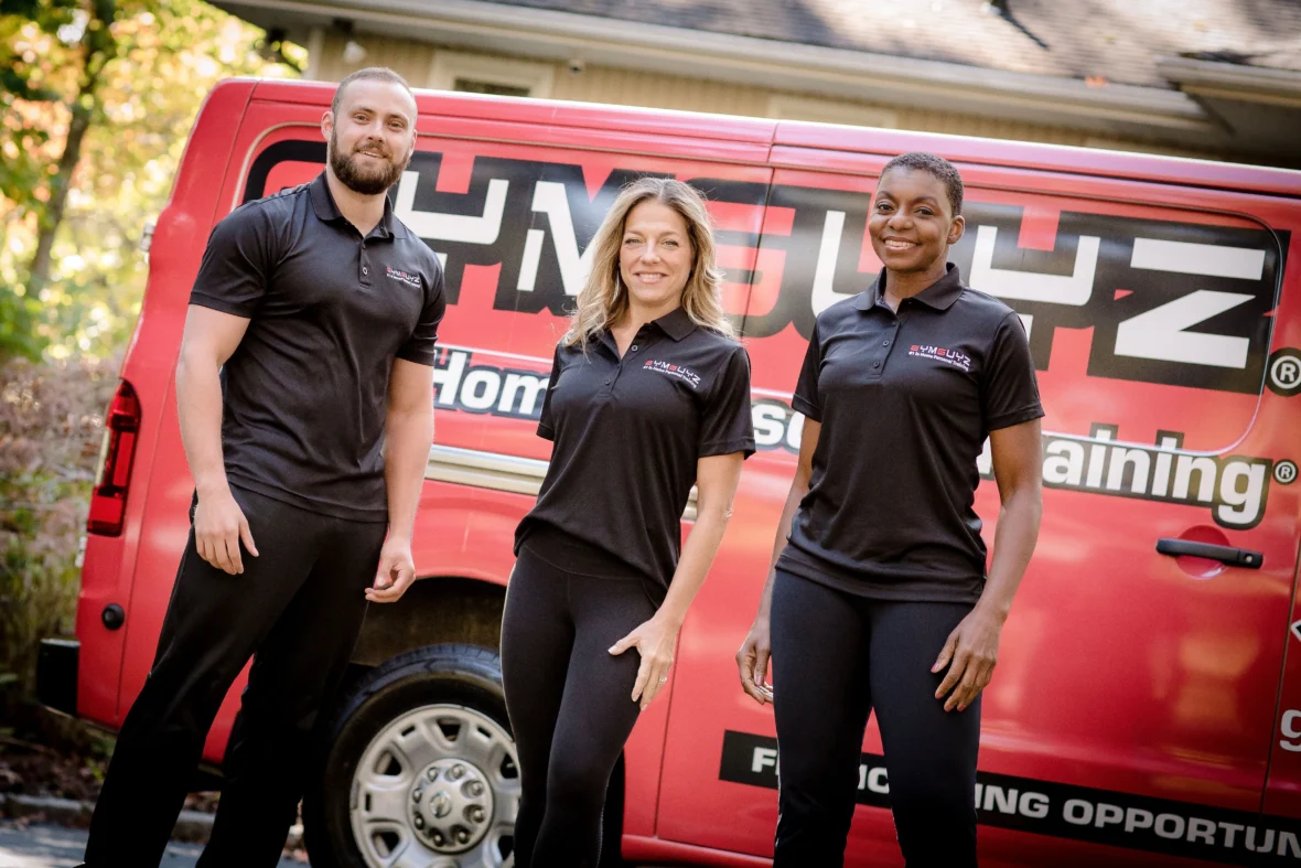 Three personal trainers standing in front of a mobile personal training van