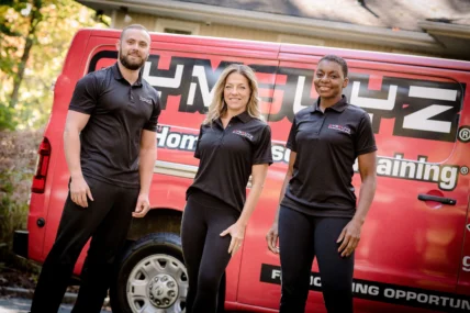 Three personal trainers standing in front of a mobile personal training van