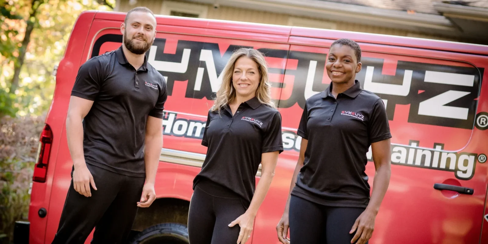 Three personal trainers standing in front of a mobile personal training van