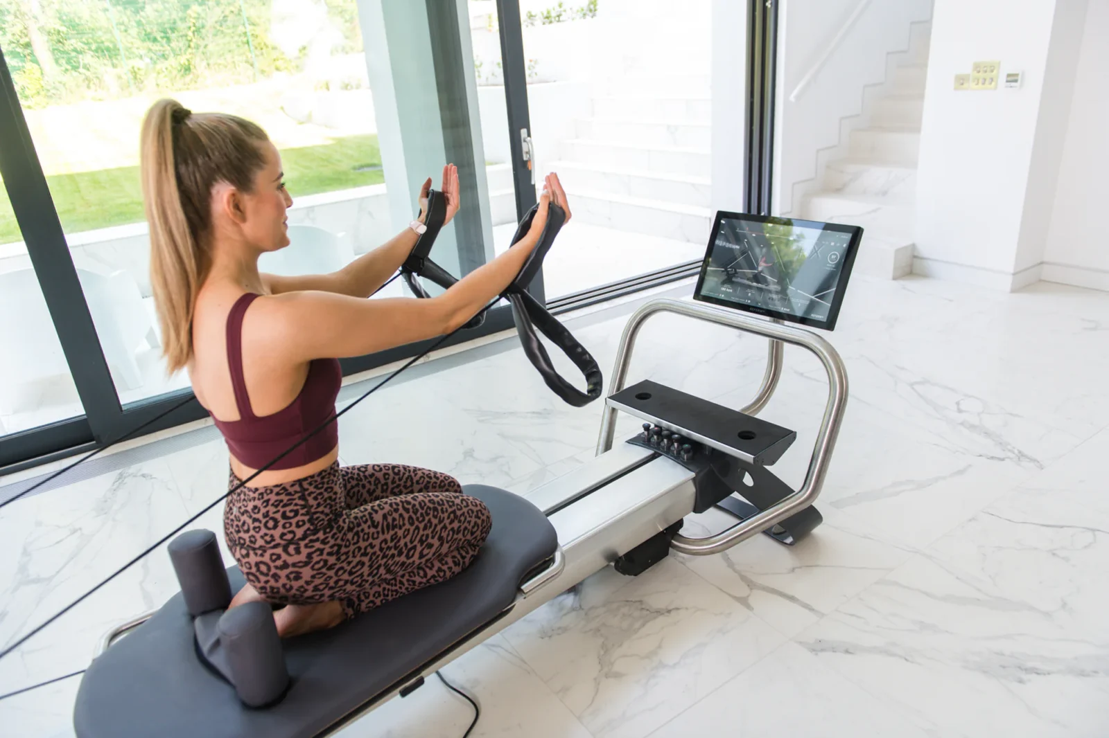 An image of a woman using a connected Pilates Reformer