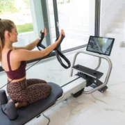 An image of a woman using a connected Pilates Reformer