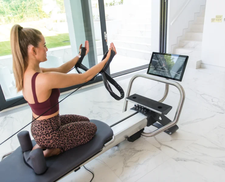 An image of a woman using a connected Pilates Reformer