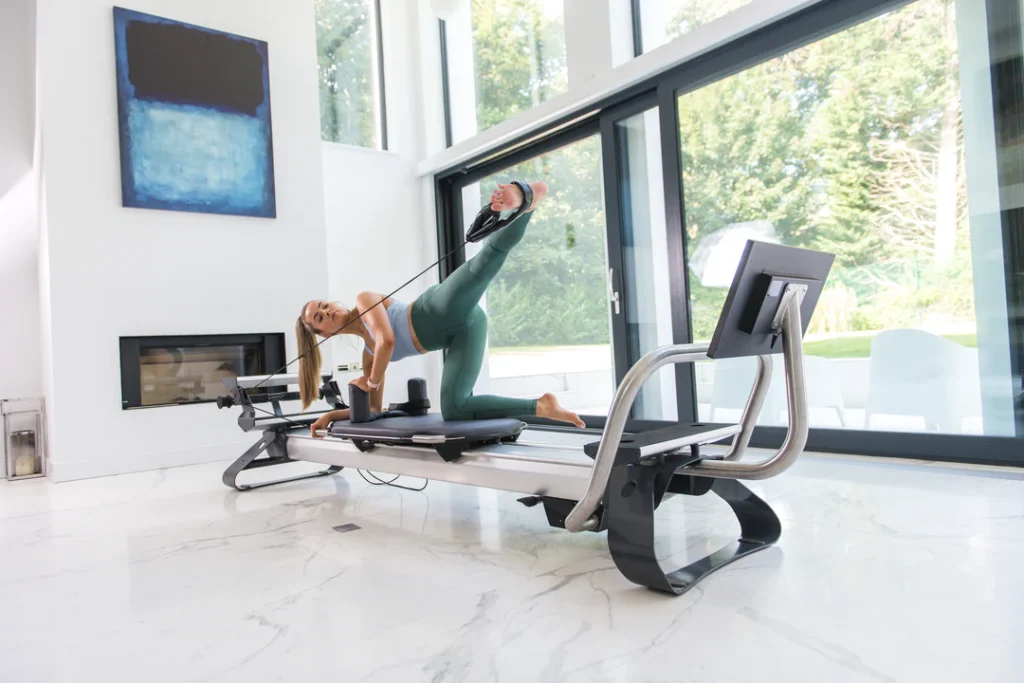 An image of a woman working out at home on a connected Pilates Reformer made by Reform RX.