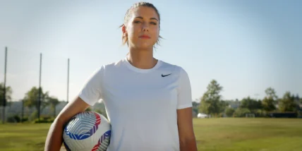 an image of former soccer star Alex Morgan holding a soccer ball on a field