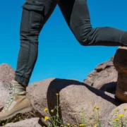 A cropped image showing the bottom half of a body walking along a rocky landscape with flowers.