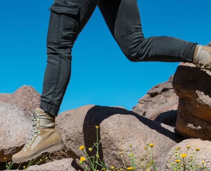 A cropped image showing the bottom half of a body walking along a rocky landscape with flowers.