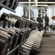 an image of a weight rack at a gym with a woman standing at the end lifting weights