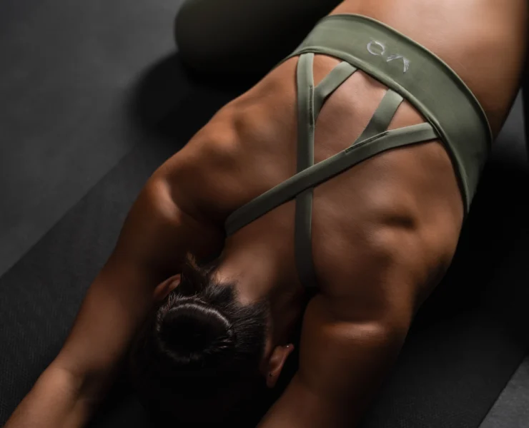 an image of a woman wearing a ASRV women's activewear and stretching on a yoga mat