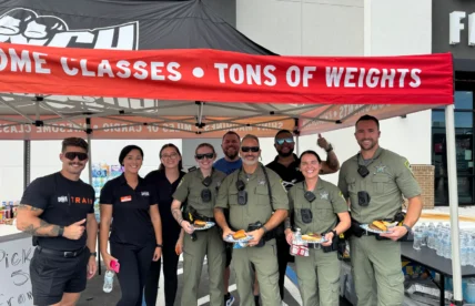 Crunch Fitness staff members and local community members gather in front of a Florida gym
